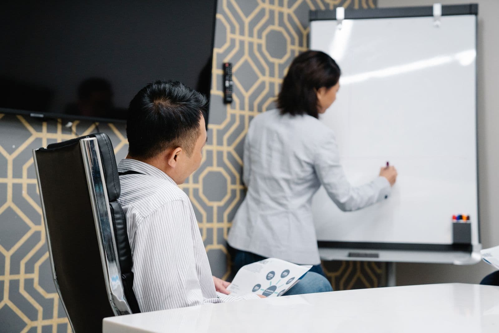Two colleagues working through a plan at a whiteboard