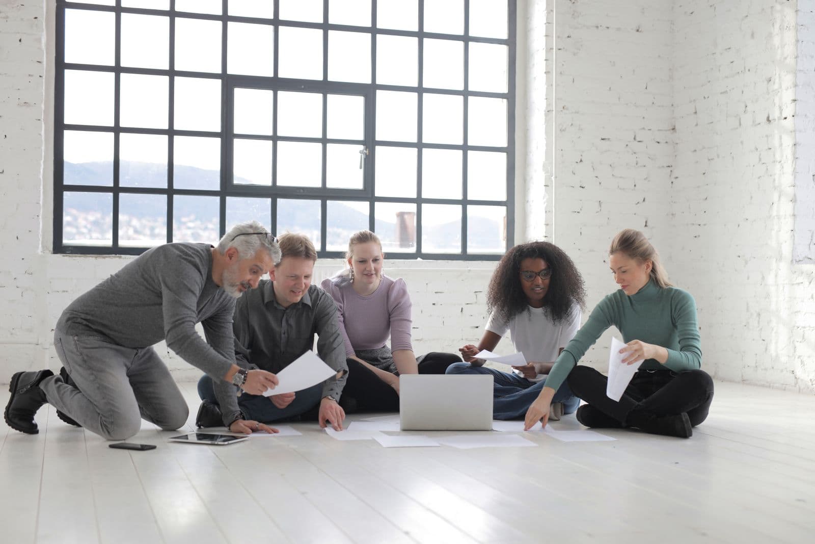 A team sitting on the floor reviewing printed layouts together